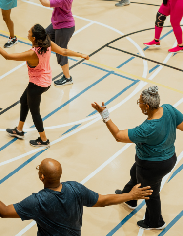 A gym of seniors dances in sync during a workout class