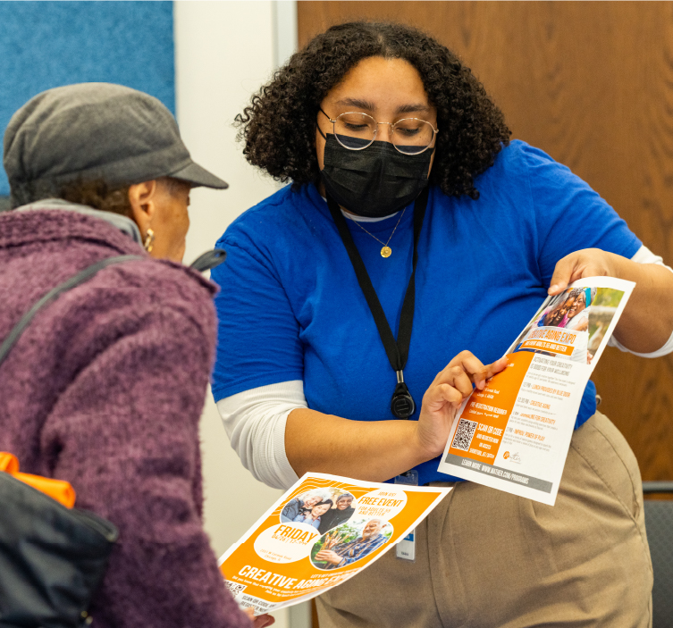 Worker shows flyer to community member at Neighborhood Center