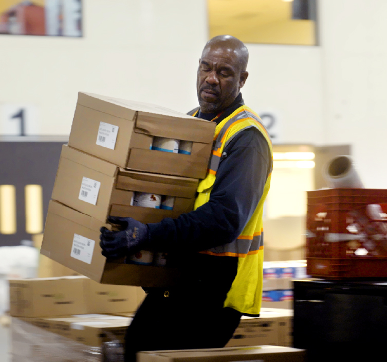 Food bank worker carries boxes of food