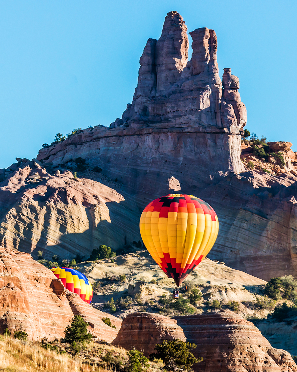 Hot air balloons flying over Castle Rock in the Red Rock Canyon near Gallup, New Mexico.