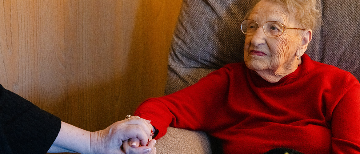 Older woman holds a companion's hand