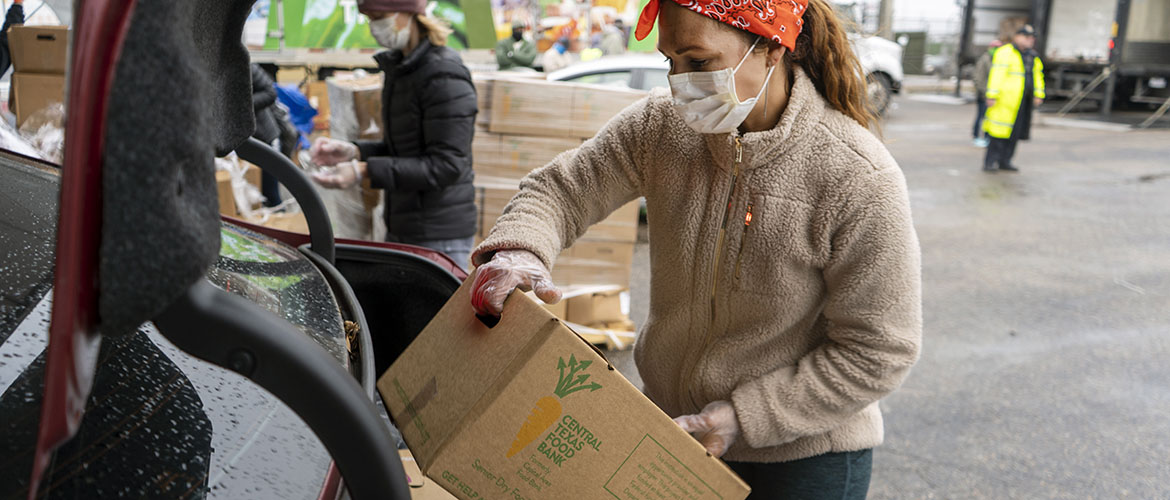 A food bank volunteer loads boxes into cars