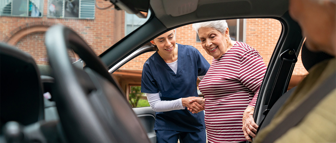 female nurse helps elderly woman into car