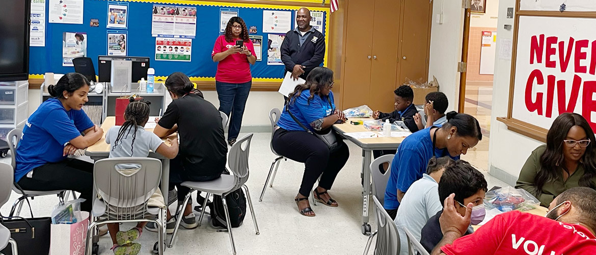 Volunteers, teachers and students talk in a classroom. 