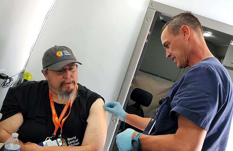 A health care worker prepares to give a man a vaccination.