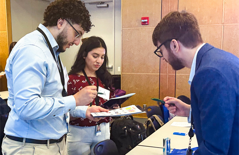 Young students fill out paperwork with help of man in suit